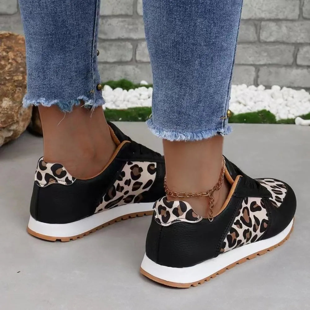 Black leopard print panel runner sneakers with white soles and a gold ankle chain.