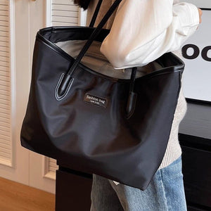 Large black Oxford cloth tote bag with leather trim and dual straps.