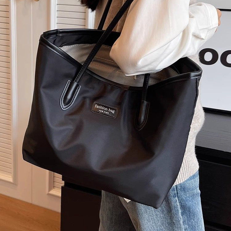 Large black Oxford cloth tote bag with leather trim and dual straps.