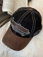 Distressed denim baseball cap in black with brown brim and embroidered "American" detail.