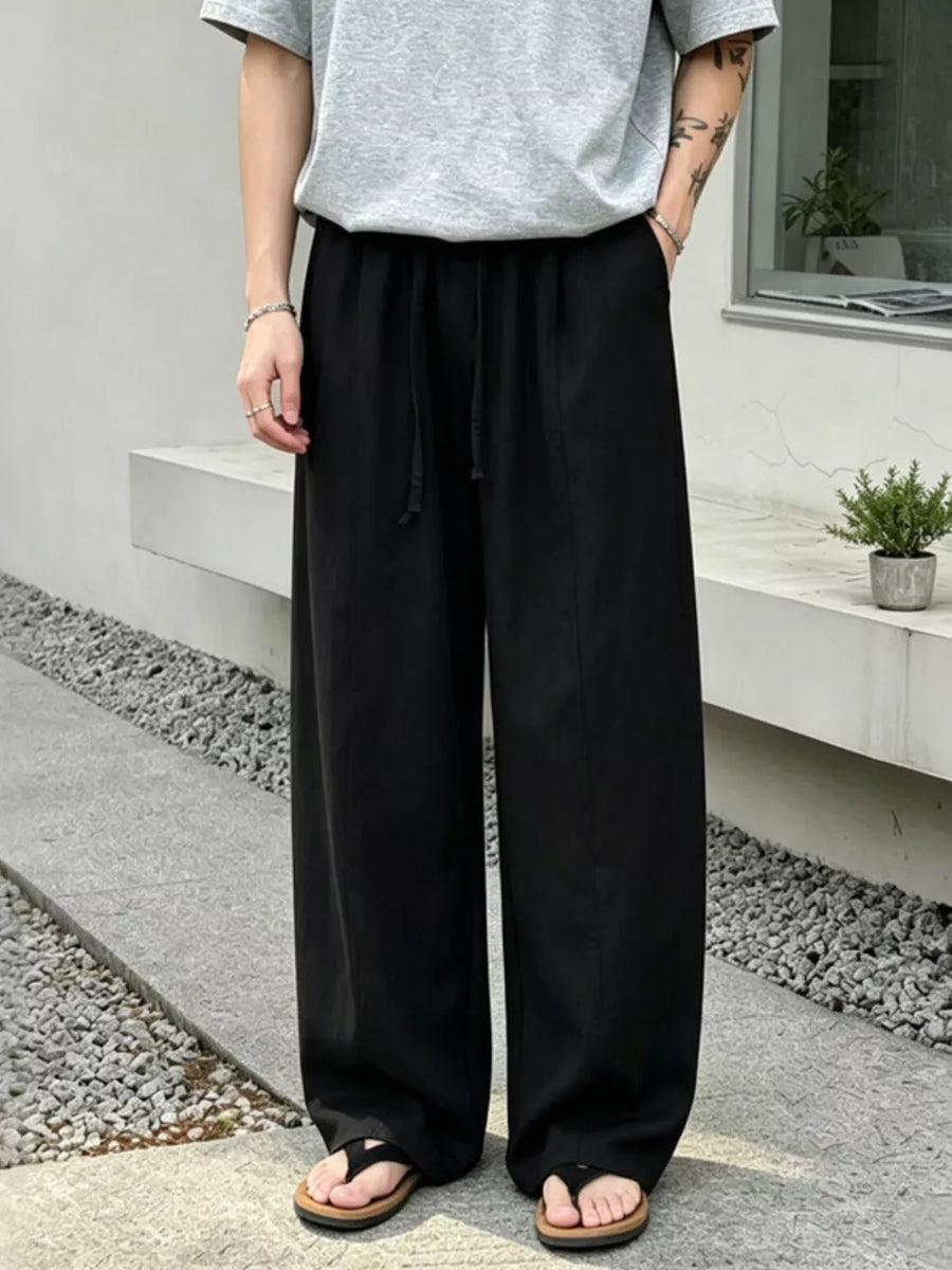 Black wide-leg sweatpants with drawstring waist and pockets, styled casually.