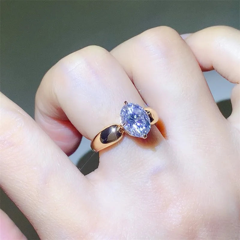 Gold ring with oval moissanite solitaire on a finger