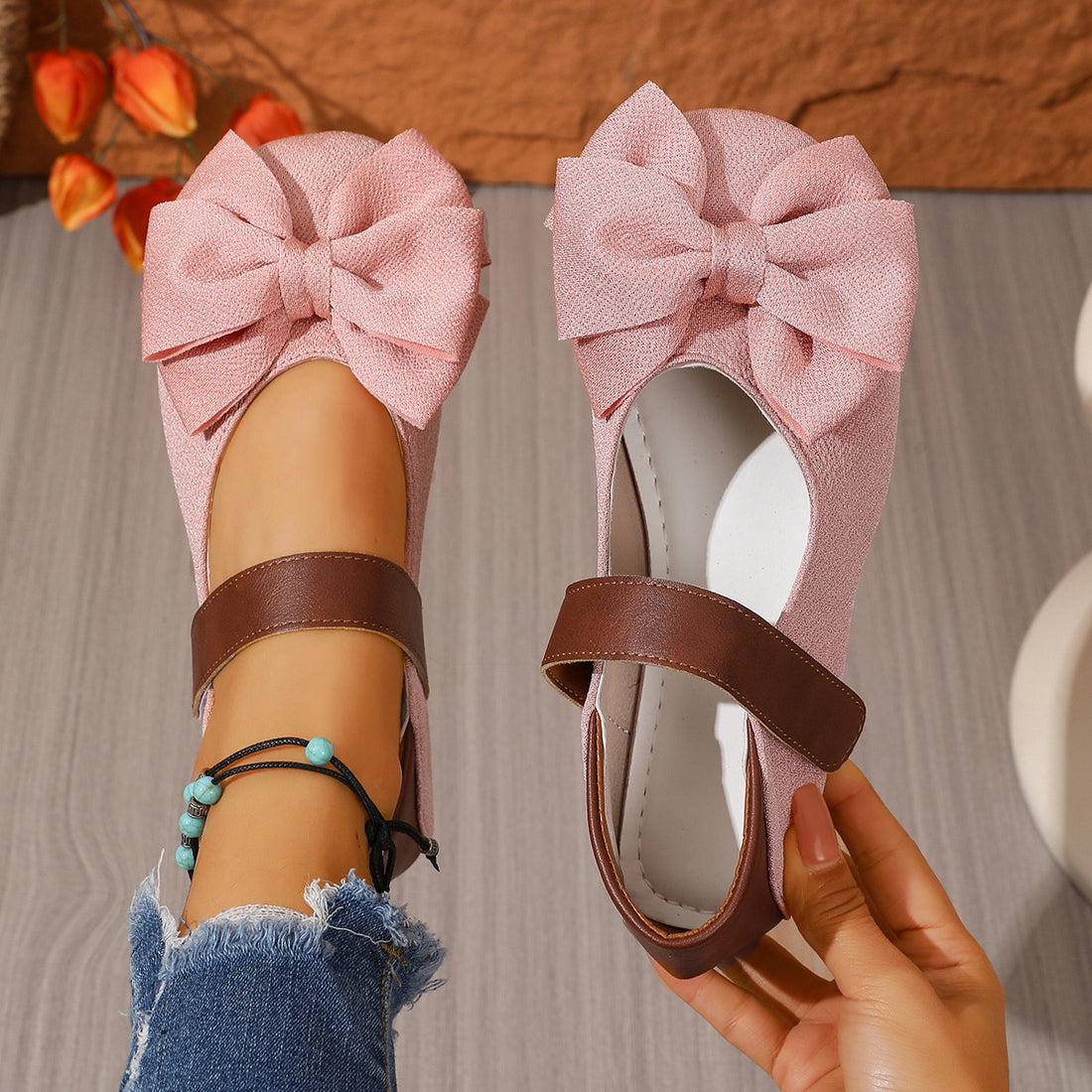 Pink textured round toe flats with bow detail and brown strap.