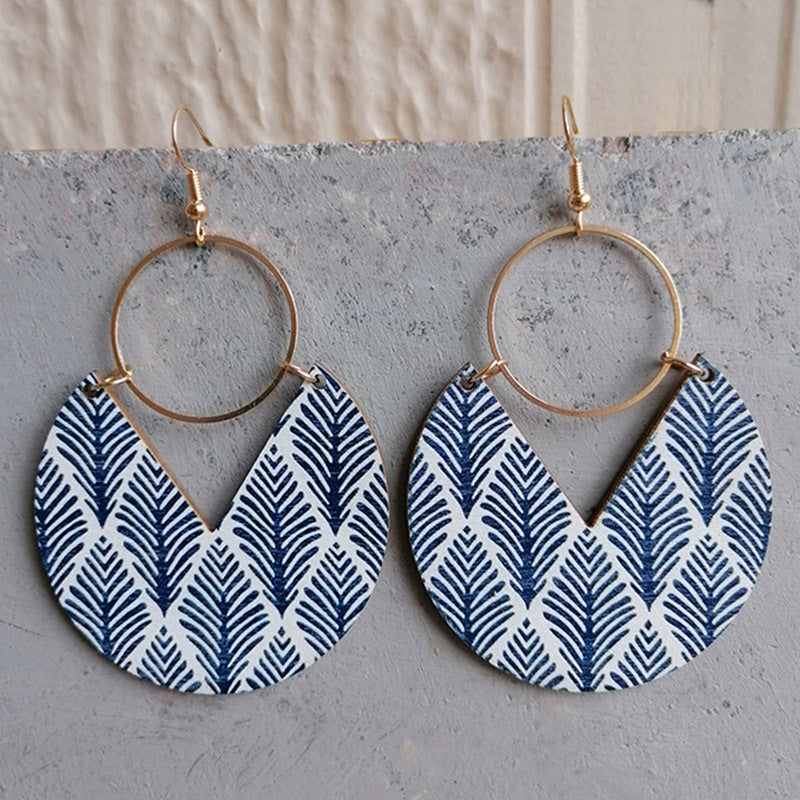 Geometric wood drop earrings with blue feather pattern and gold hoops.