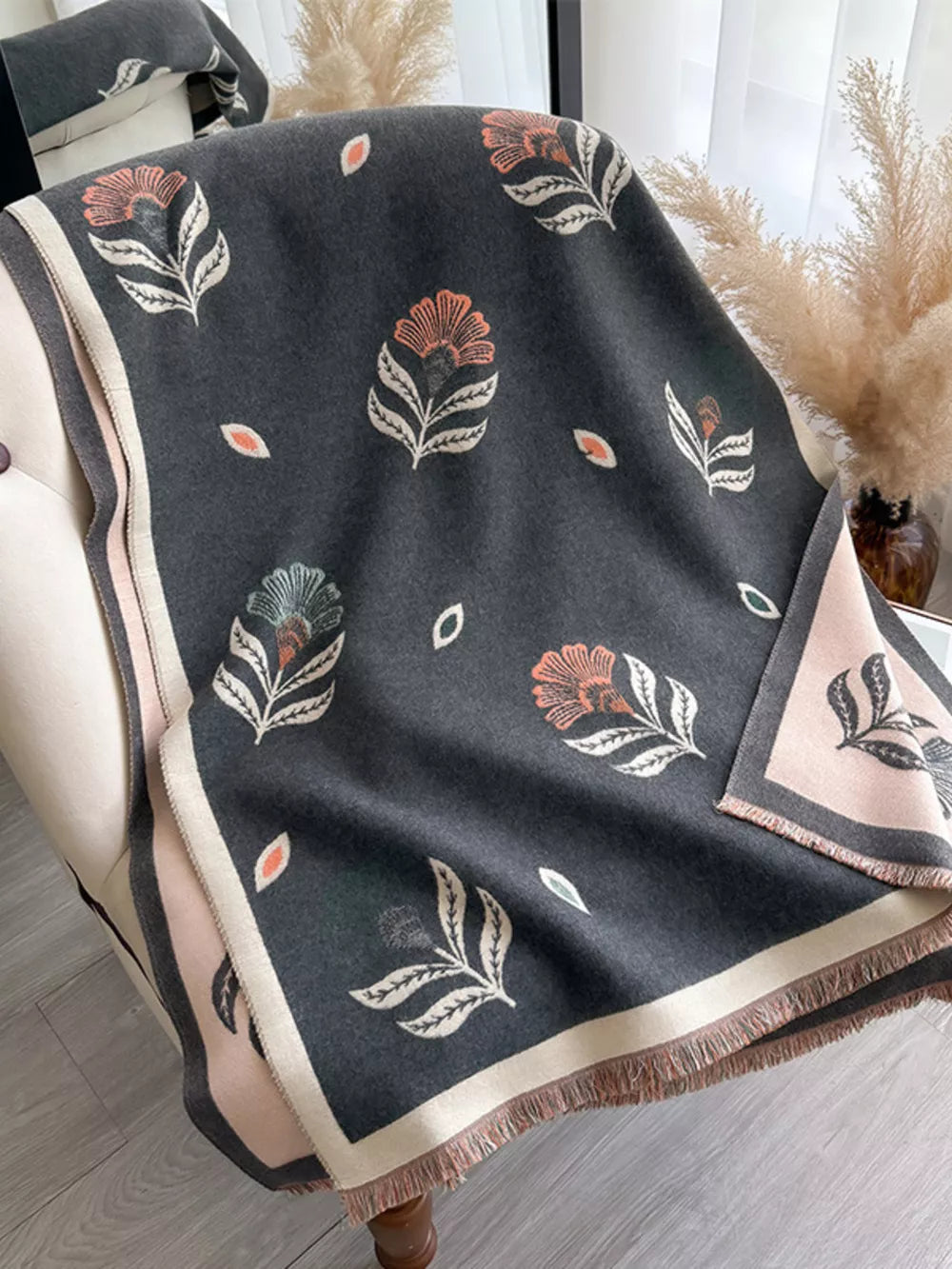 Floral print fringed shawl in gray with pink and cream trim, featuring botanical motifs.