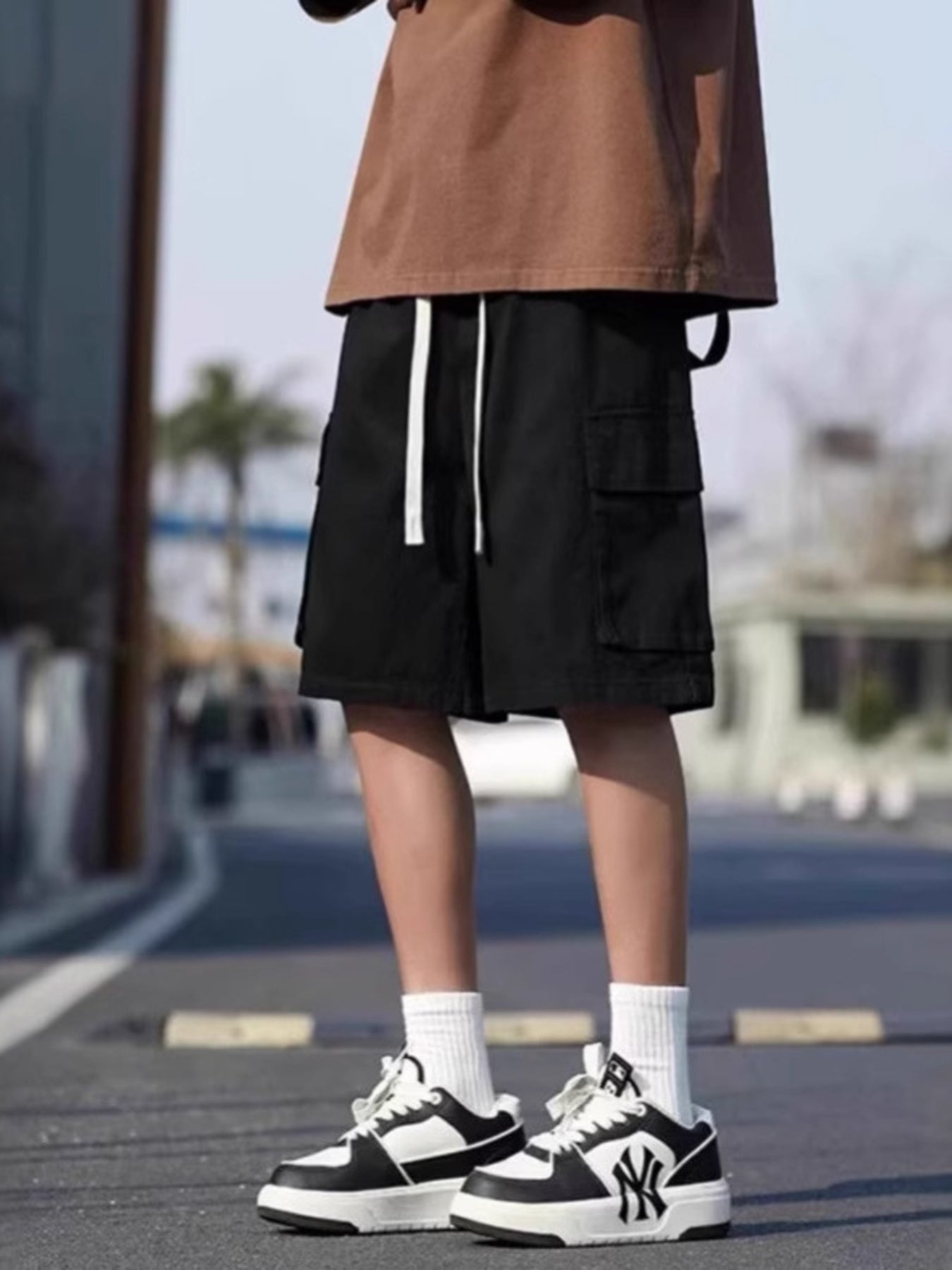 Men's black casual cargo shorts with white drawstring and side pockets.