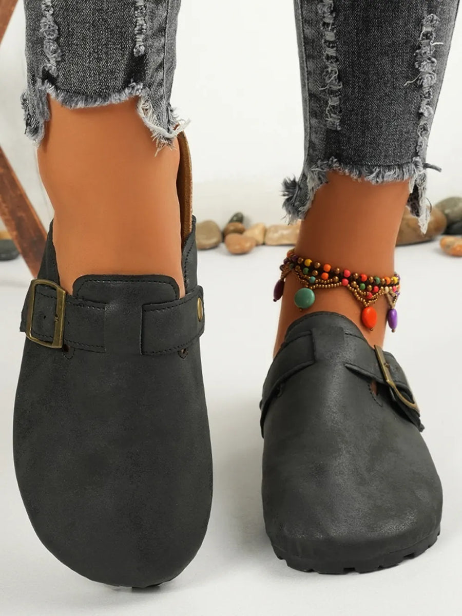Black textured suede mules with buckle detail and cork sole.