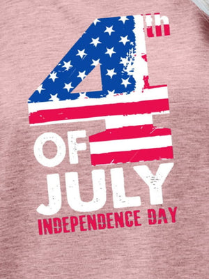 Graphic tee with 4th of July text and American flag design in red, white, and blue on a dusty pink shirt.