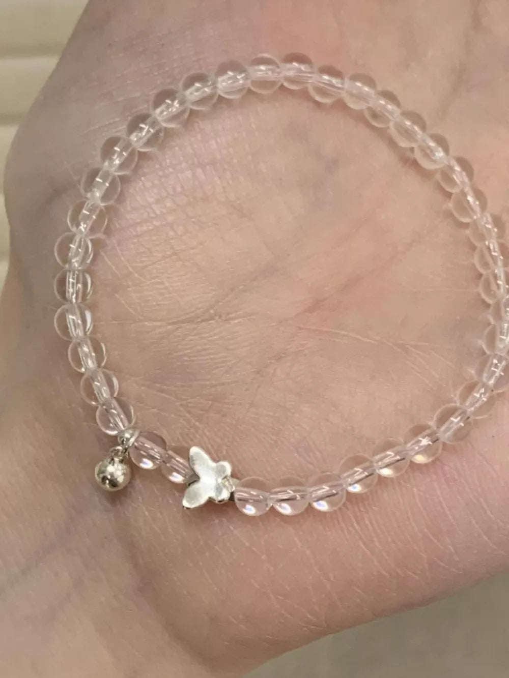 Clear crystal bead bracelet with butterfly and bell charms.