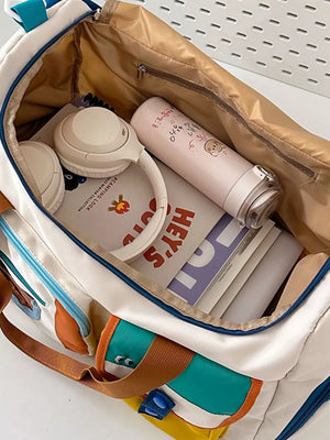 Vibrant multi-pocket nylon travel bag with color block details, shown packed with headphones and a water bottle.