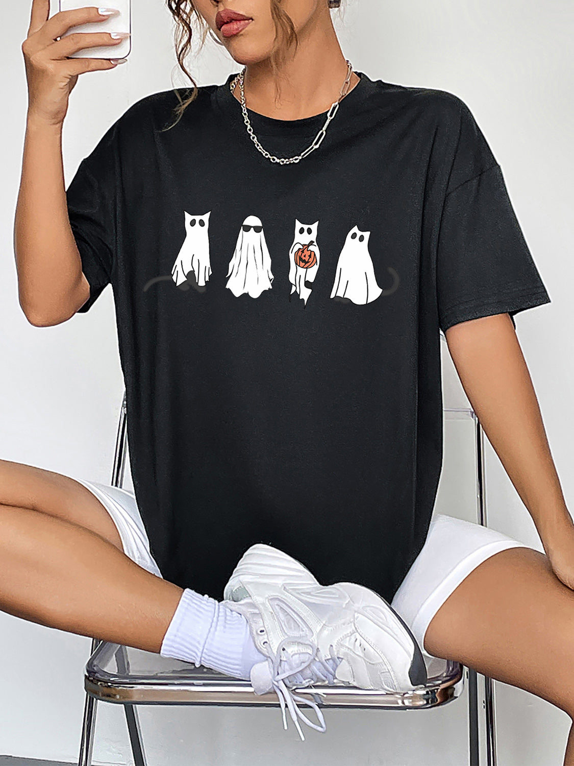 Black crew neck t-shirt with a graphic of four white ghosts, one holding a pumpkin.