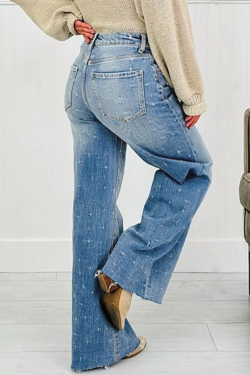 High-rise light wash denim jeans with distressed details and raw hem.
