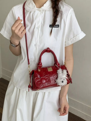 Charming mini crossbody bag in burgundy with bow detail and fluffy charm.