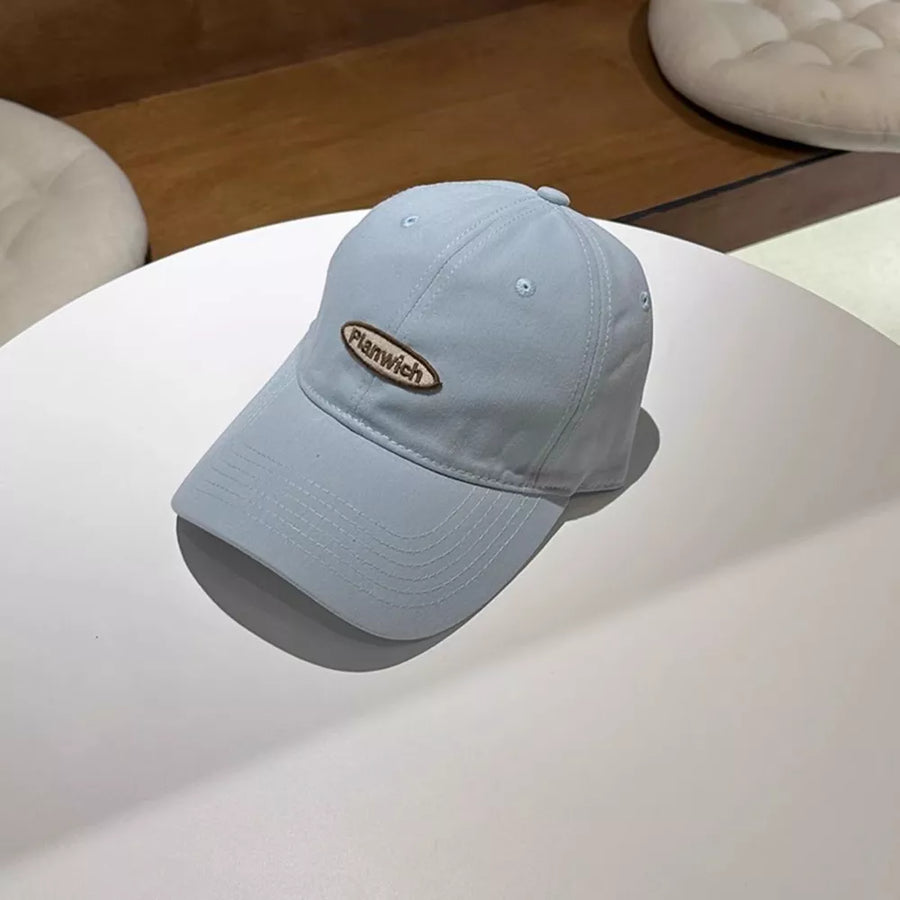 Light blue baseball cap with oval embroidered logo detail