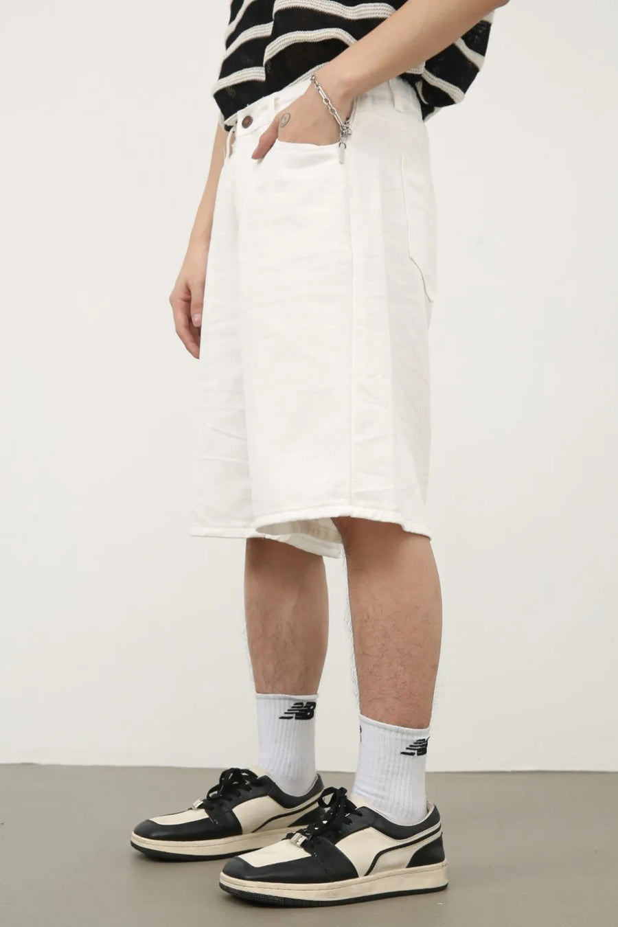 White textured denim bermuda shorts with a raw hem, shown on a model.