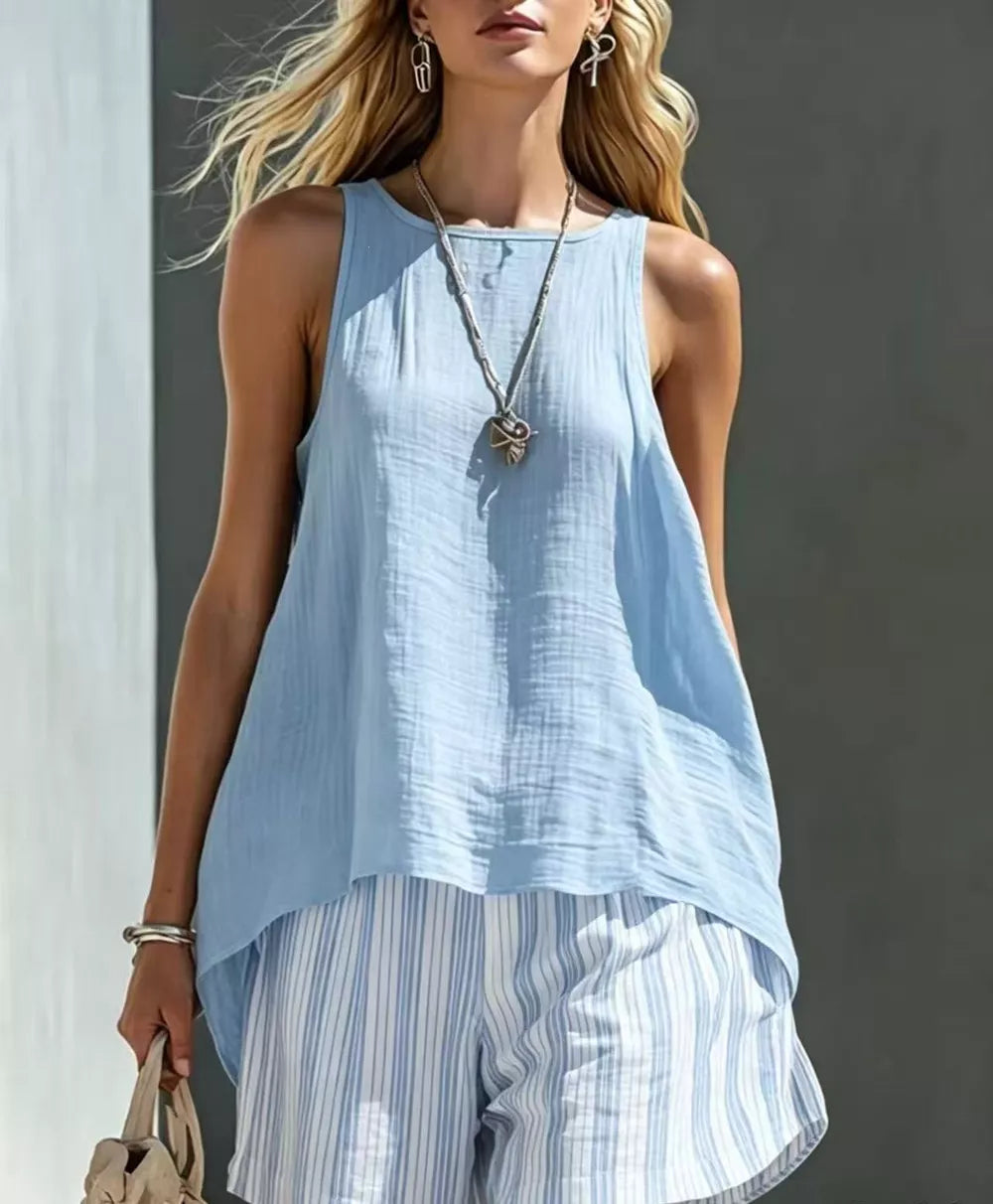 Light blue sleeveless tunic with round neck and high-low hem, paired with white and blue striped shorts.