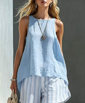 Light blue sleeveless tunic with round neck and high-low hem, paired with white and blue striped shorts.