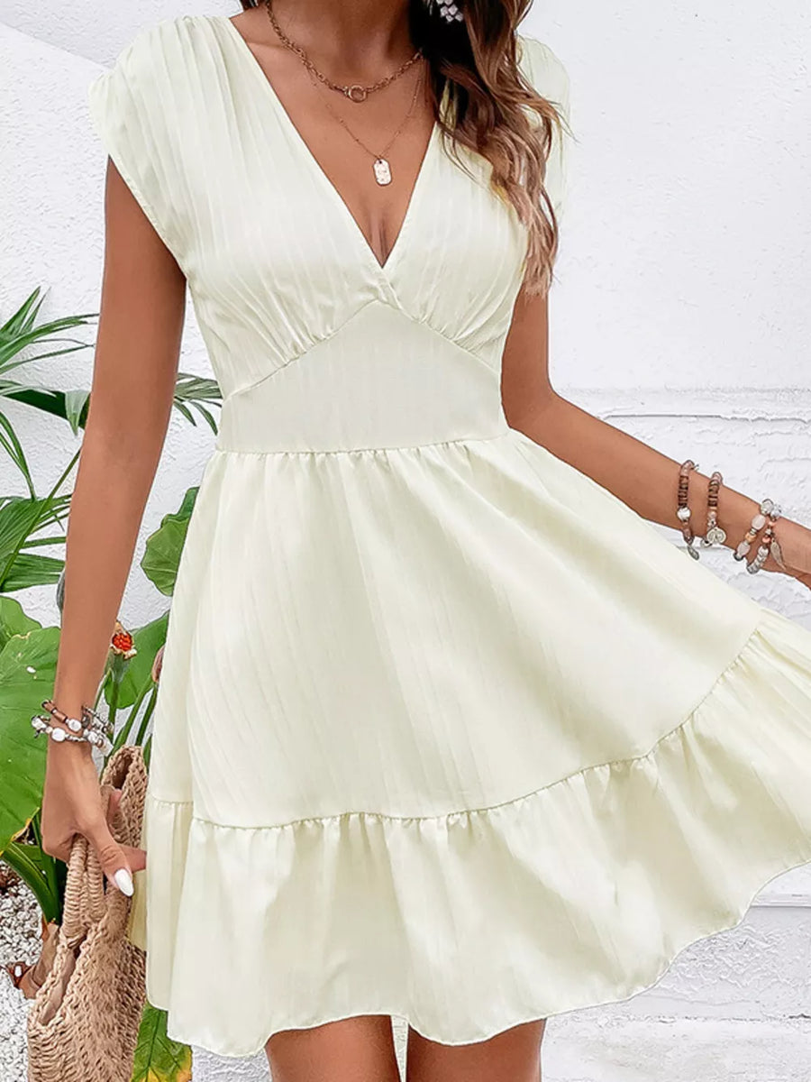Tiered cap sleeve mini dress in white with a V-neck and ruffled hem.