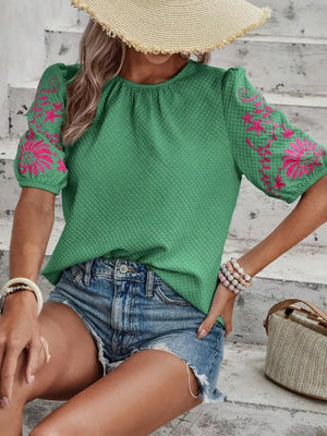 Green embroidered puff sleeve blouse with textured fabric and pink floral detail.