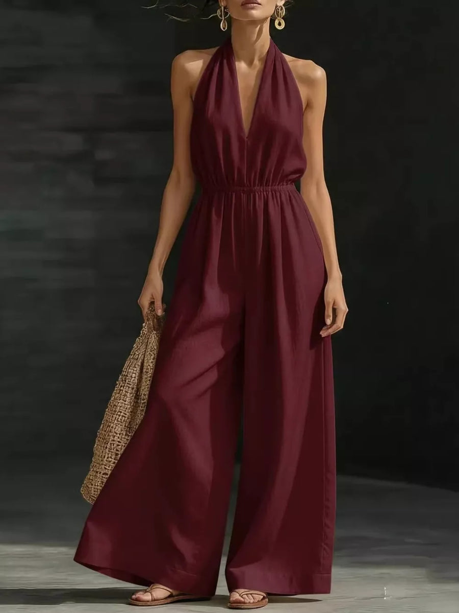 Burgundy wide-leg halter jumpsuit with elastic waist and deep V-neck.