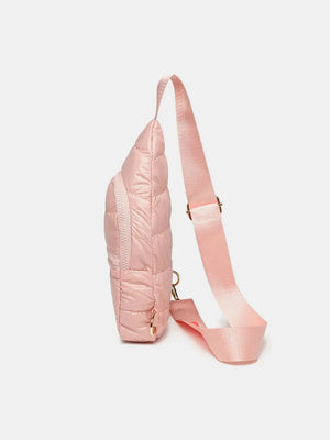Glossy padded sling bag in pink with quilted detail and adjustable strap.