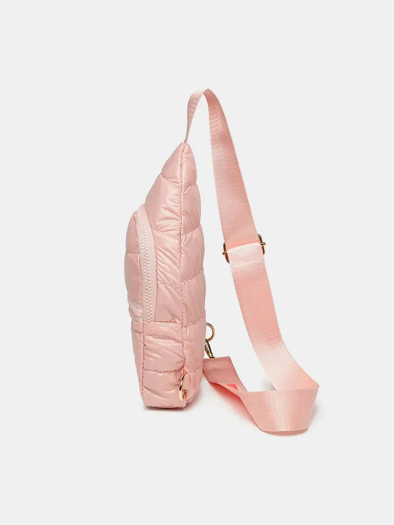 Glossy padded sling bag in pink with quilted detail and adjustable strap.