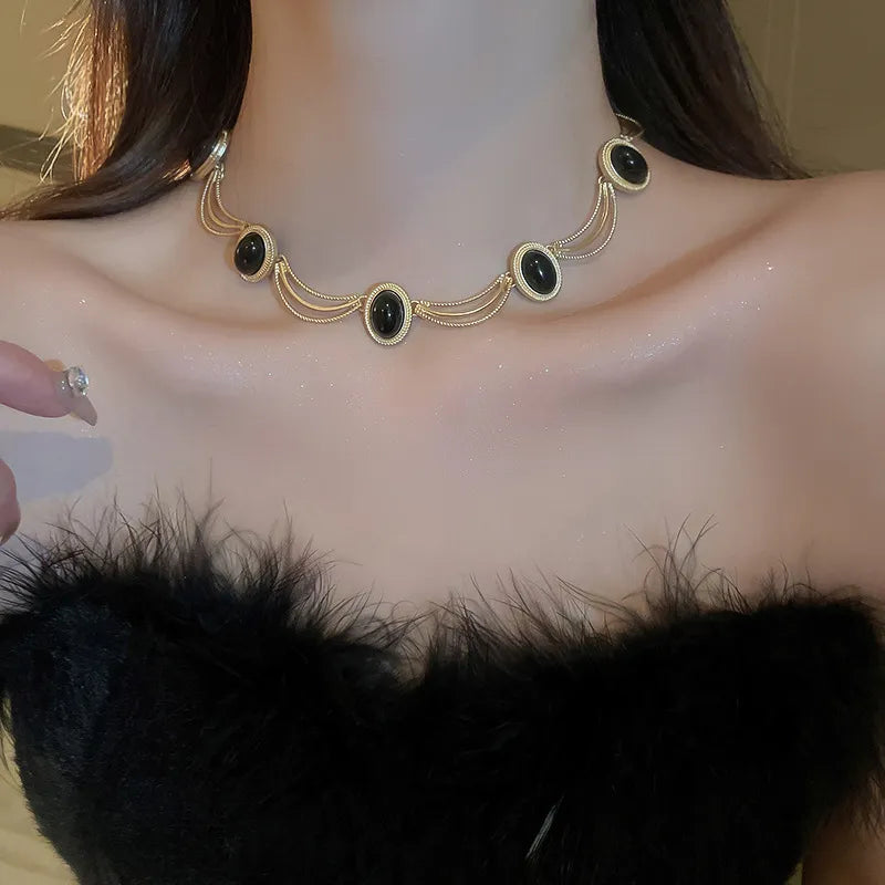 Gold oval gemstone necklace with layered chains and ornate detailing.