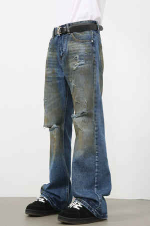 Distressed flare jeans in medium wash denim with patina and ripped details.