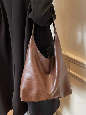 Brown sculptural PU leather tote bag with slouchy silhouette and single strap.