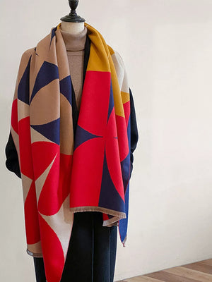 Geometric patterned soft scarf with fringes in red, blue, tan, and yellow, with frayed edges.