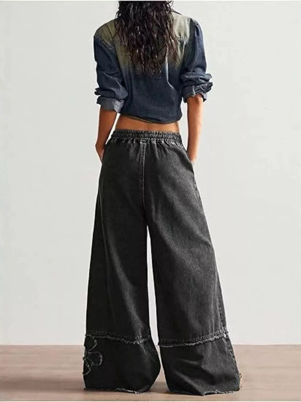 Black wide leg denim pants with elastic waist and frayed hem detail.