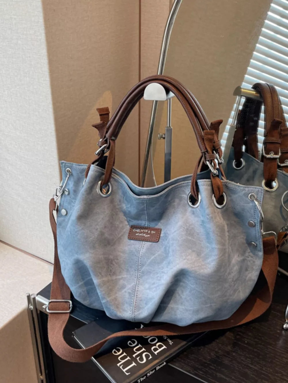 Blue slouchy crossbody bag with brown leather straps and adjustable strap.