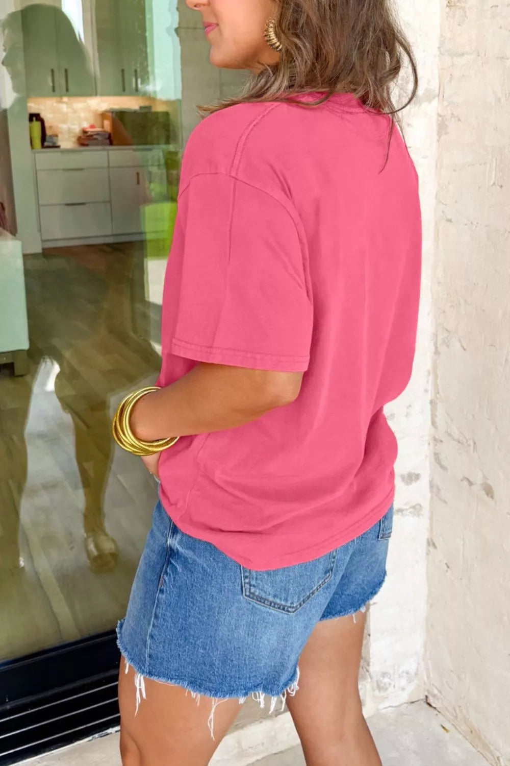Pink cotton mineral wash tee with short sleeves and a crew neck, styled with denim shorts.