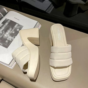 Ivory padded platform mules with a block heel and quilted strap detail.