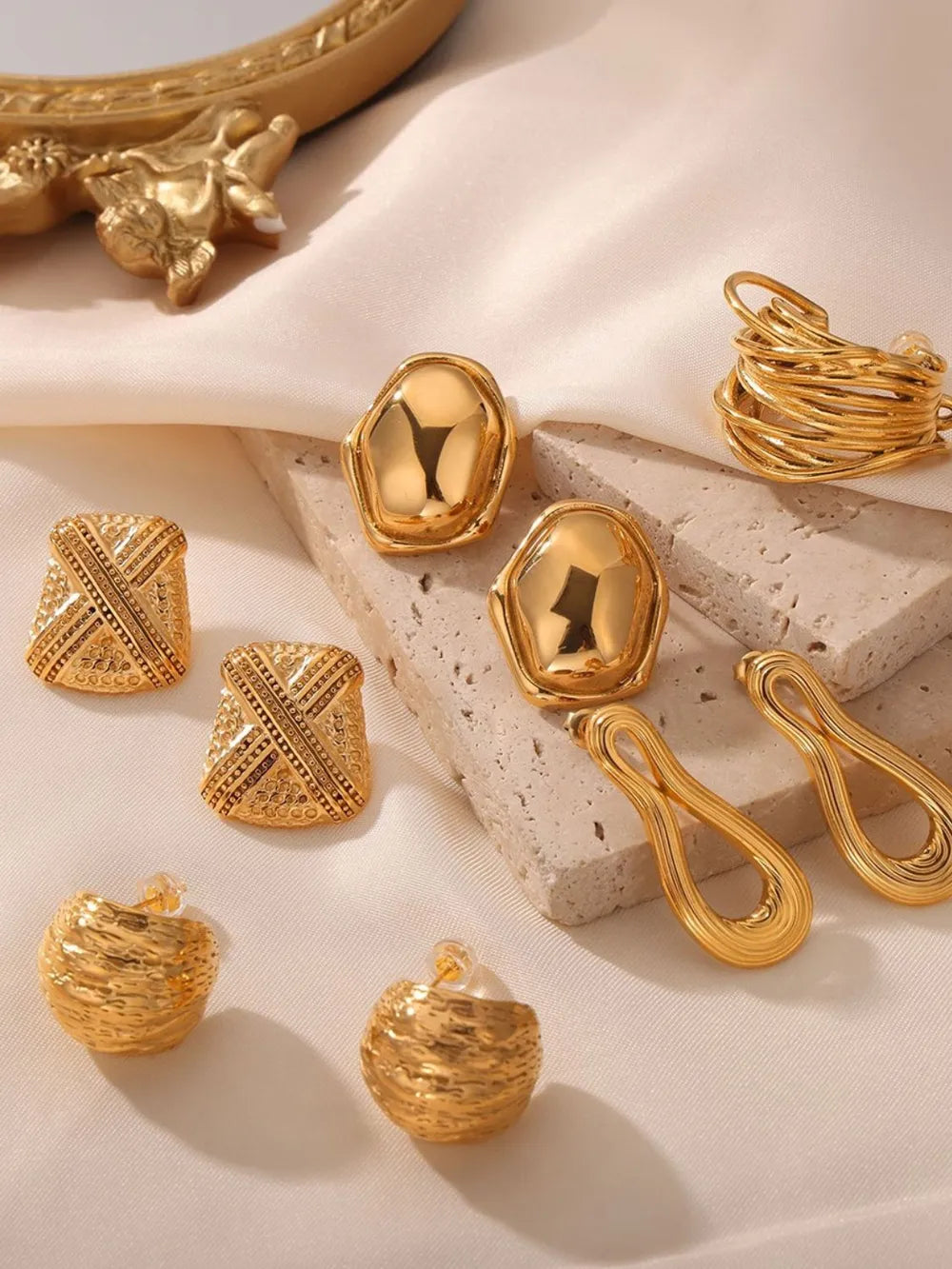 Sculptural gold-tone earrings collection featuring abstract, woven, and geometric styles.