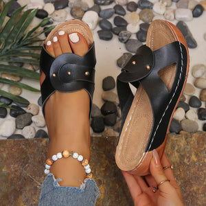 Black slip-on wedge sandals with riveted detail and broad vamp.