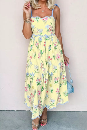 Yellow floral midi dress with bow straps, scalloped trim, and a-line cut.