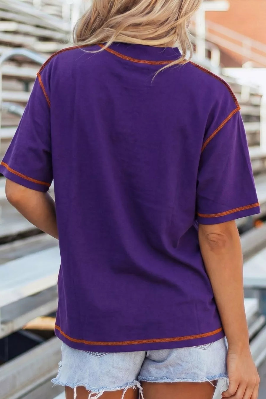 Purple cotton t-shirt with contrast orange stitching on neckline, sleeves, and hem.