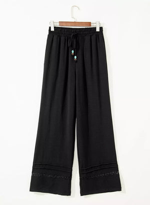 Black maternity wide-leg trousers with drawstring and beaded detail.