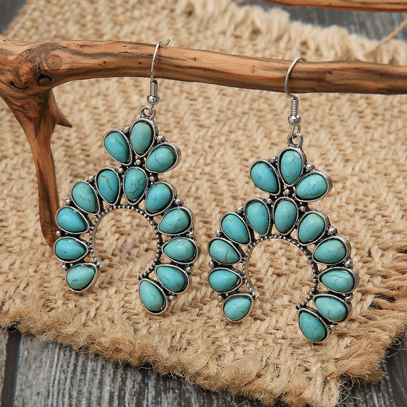 Turquoise crescent dangle earrings with alloy setting and teardrop stones.