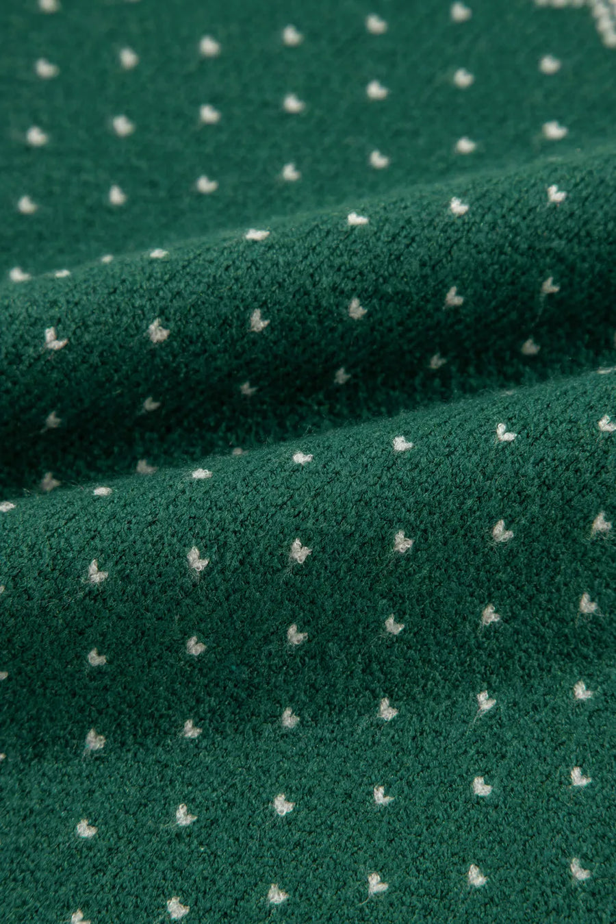 Dark green knit sweater with a white snowflake Fair Isle pattern.