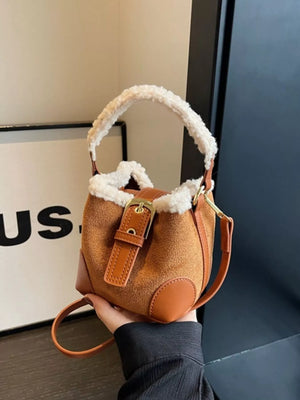 Brown suede bucket bag with fuzzy trim and crossbody strap.