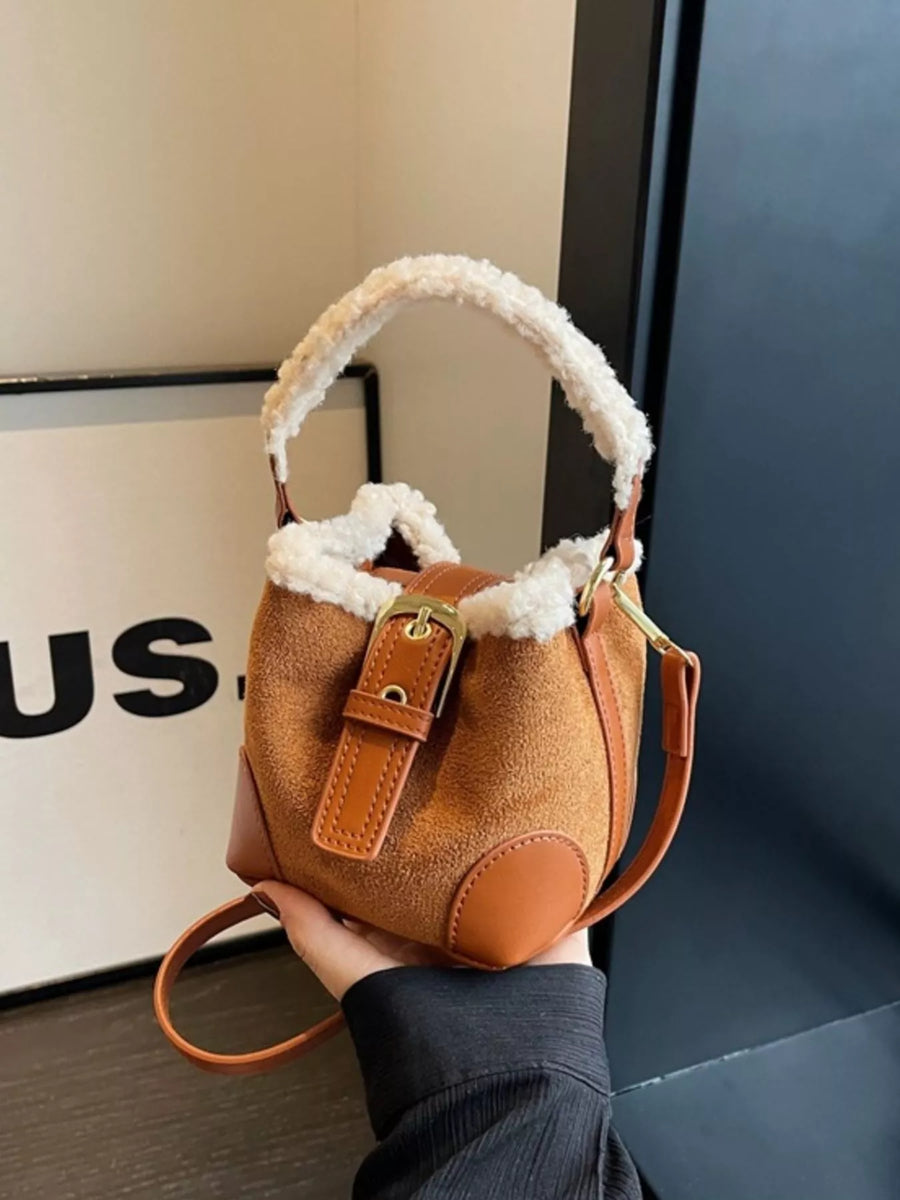 Brown suede bucket bag with fuzzy trim and crossbody strap.