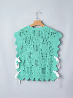 Green pointelle knit sweater with scalloped trim and side tie details.
