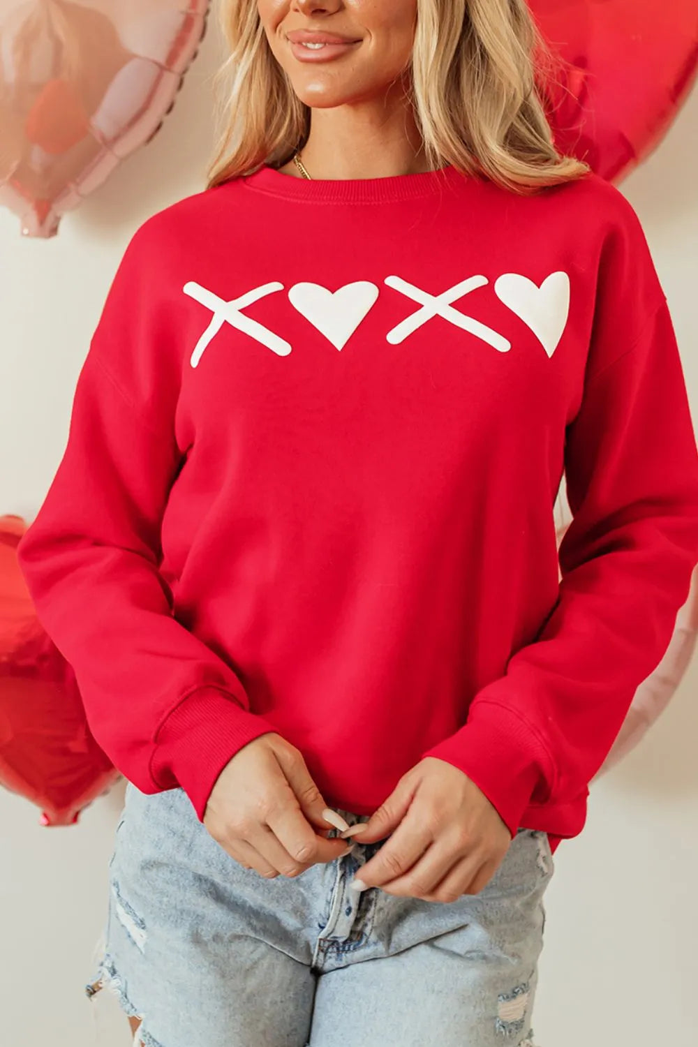 Red crewneck sweatshirt with white XOXO graphic and heart details