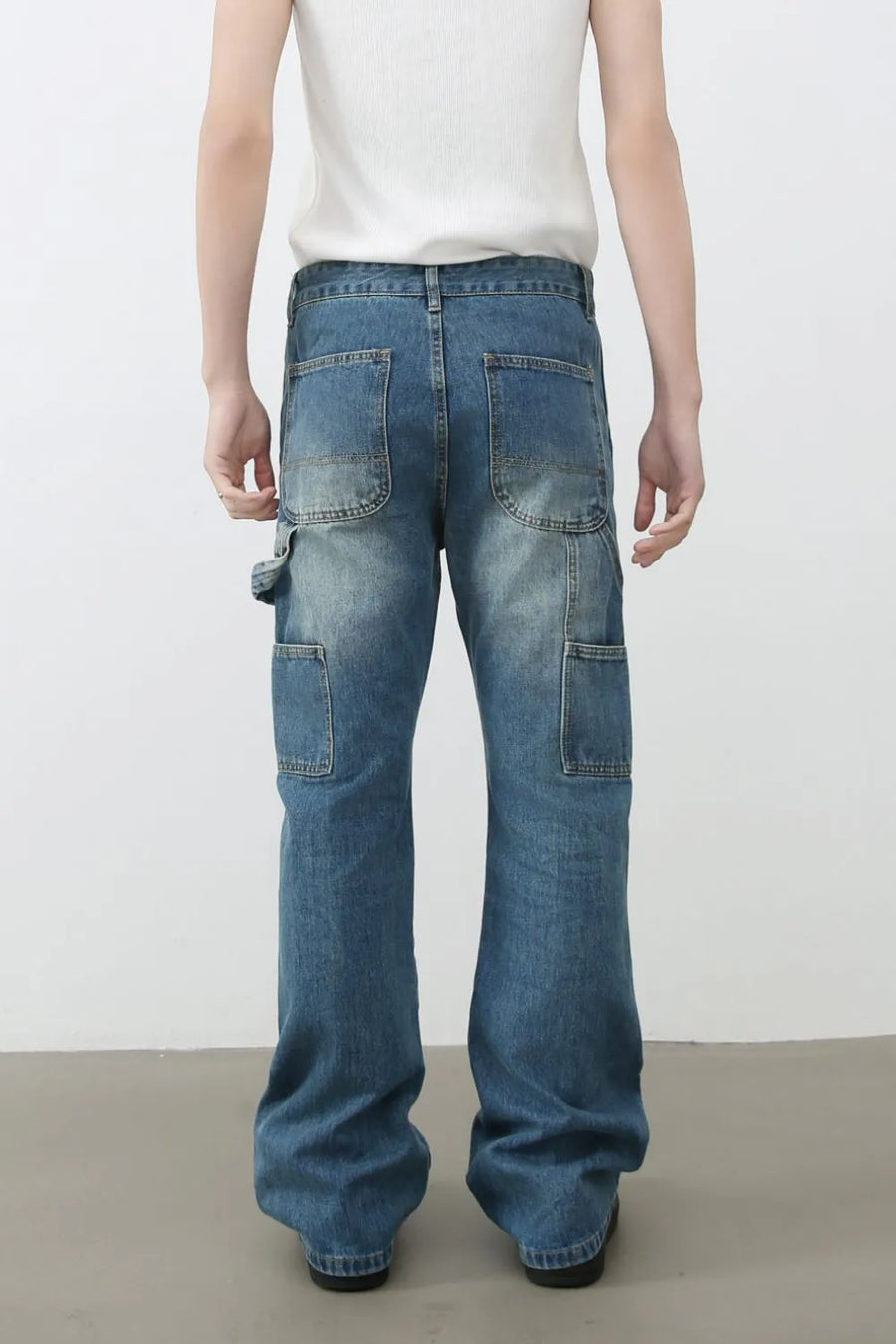 Carpenter flare jeans in medium wash denim with distressed details and multiple pockets.