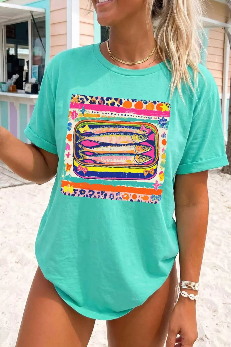 Teal cotton crew neck t-shirt with a playful sardine can graphic and colorful abstract patterns.