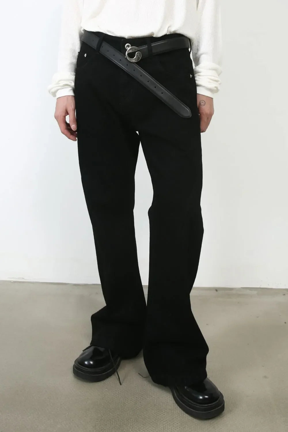 Black bootcut jeans with a black belt and silver buckle, styled with patent shoes.