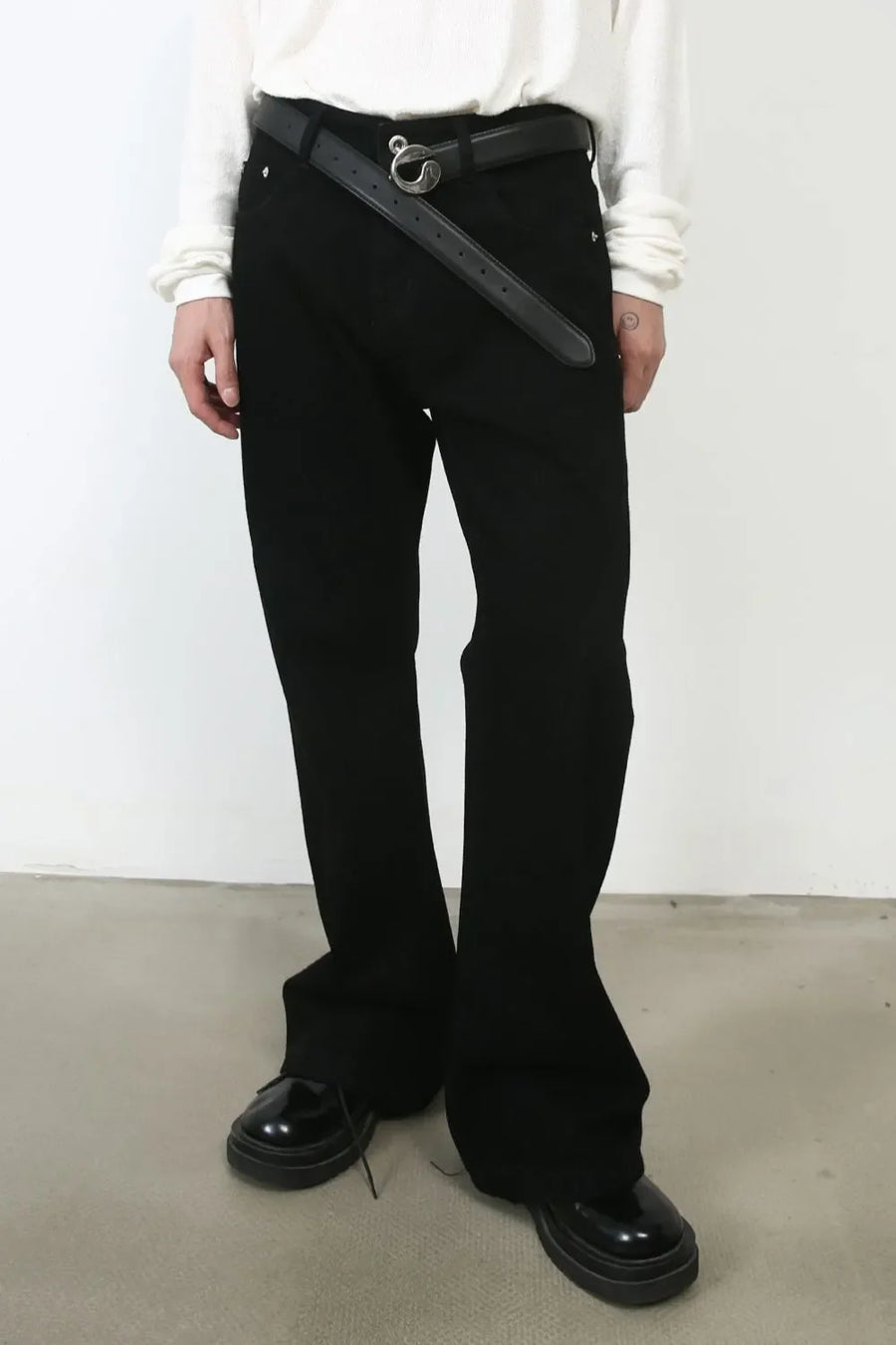 Black bootcut jeans with a black belt and silver buckle, styled with patent shoes.