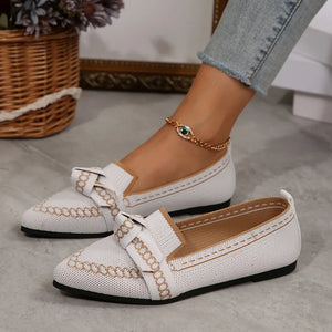 White chain-stitched knit bow pointed flats with tan trim and a gold evil eye anklet.